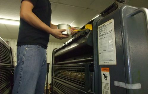 A press worker adding yellow ink to the press.